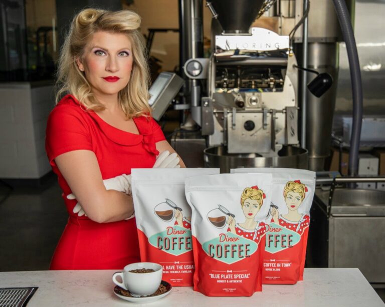 Karen Weckerly of COROCO Coffee Roaster Collective with Diner Coffee bags beside the coffee roaster